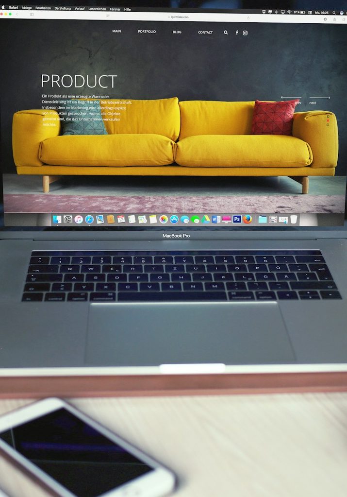 Laptop mit gelbem Sofa und Smartphone Laptop mit Anzeige eines gelben Sofas, davor ein Smartphone.