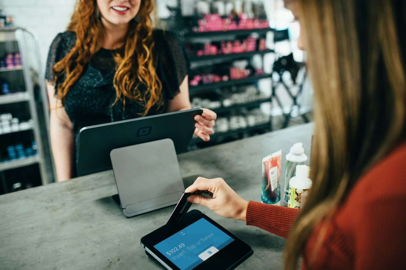 Zwei Frauen im digitalen Austausch Zwei Frauen sitzen am Tisch und unterhalten sich, beide mit Tablets.